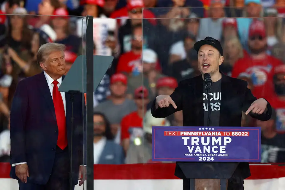 Tesla CEO Elon Musk speaks at a rally while Republican presidential nominee Donald Trump looks on, in Butler, Pennsylvania. 