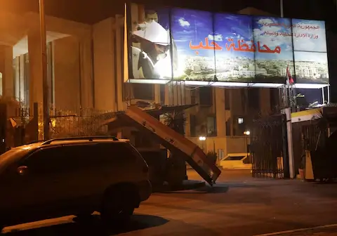 A car parked near a torn poster of Syria's President Bashar al-Assad, as rebels claim to have reached the heart of Aleppo, Syria.