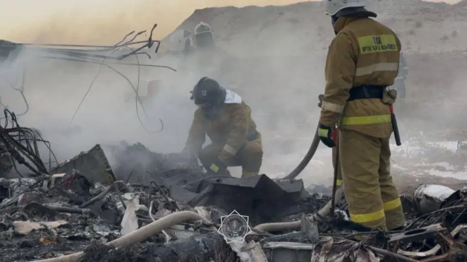 Emergency services extinguishing fire at plane crash wreckage in Kazakhstan.