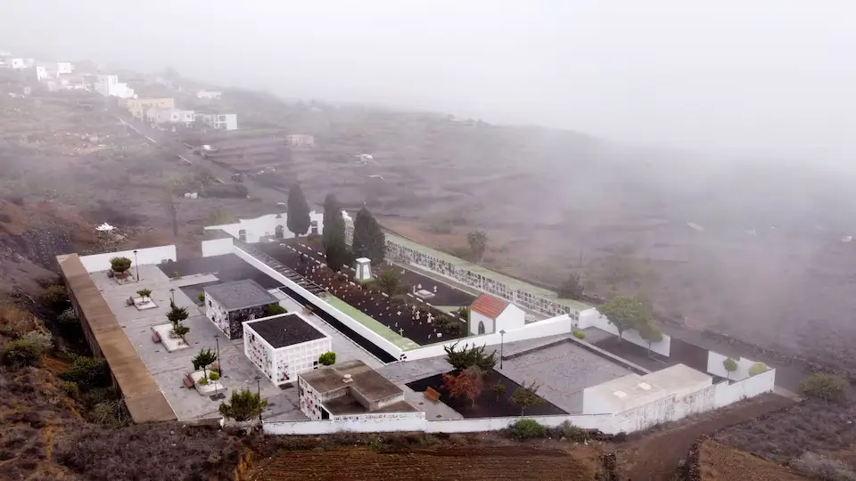 Drone perspective of El Pinar cemetery on El Hierro, showing burial sites of unidentified migrants against island landscape.