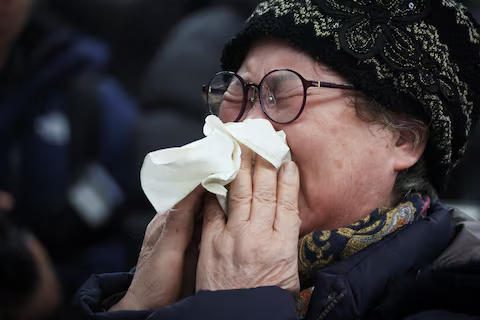 A grief-stricken relative of a plane crash victim breaks down emotionally while being comforted by others in the airport's waiting area.