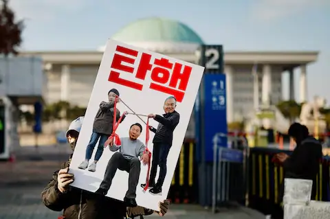 A protester holds a banner reading "impeachment," calling for the removal of President Yoon Suk Yeol in Seoul.