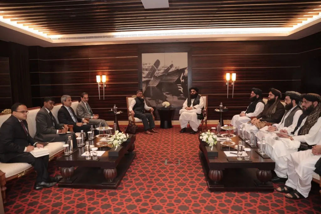 Indian and Afghan delegations seated across from each other during diplomatic talks in a formal meeting room with distinctive red carpeting.