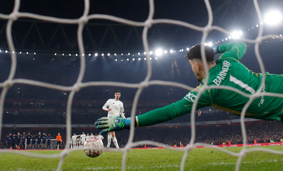 A dramatic side view of Manchester United goalkeeper Altay Bayindir stretching to make a crucial save from Kai Havertz's penalty during the FA Cup shootout at the Emirate.