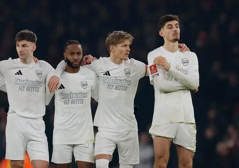 Arsenal's Kai Havertz stands with his teammates during the tense penalty shootout against Manchester United, showing the collective anxiety of the moment at the Emirates Stadium.